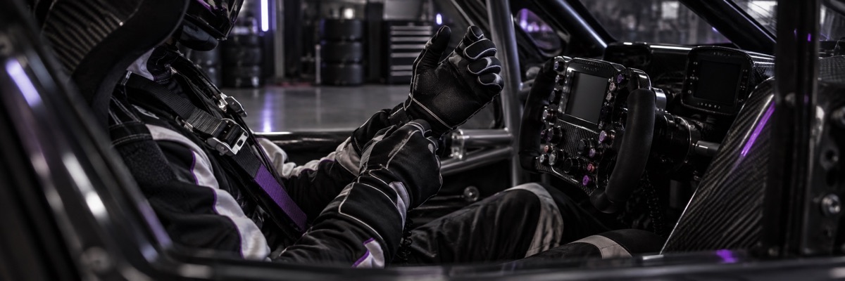 A racing driver adjusts a glove while preparing inside a GT car cockpit