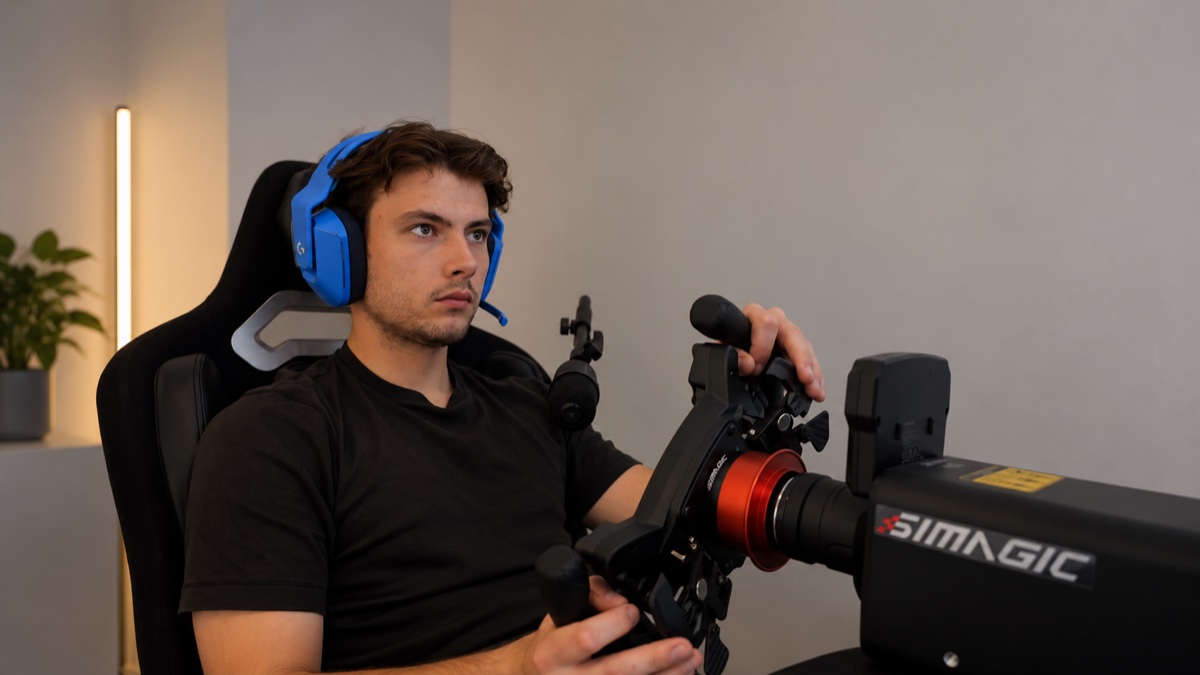 A racing driver focused at a simulator wheel while wearing a headset